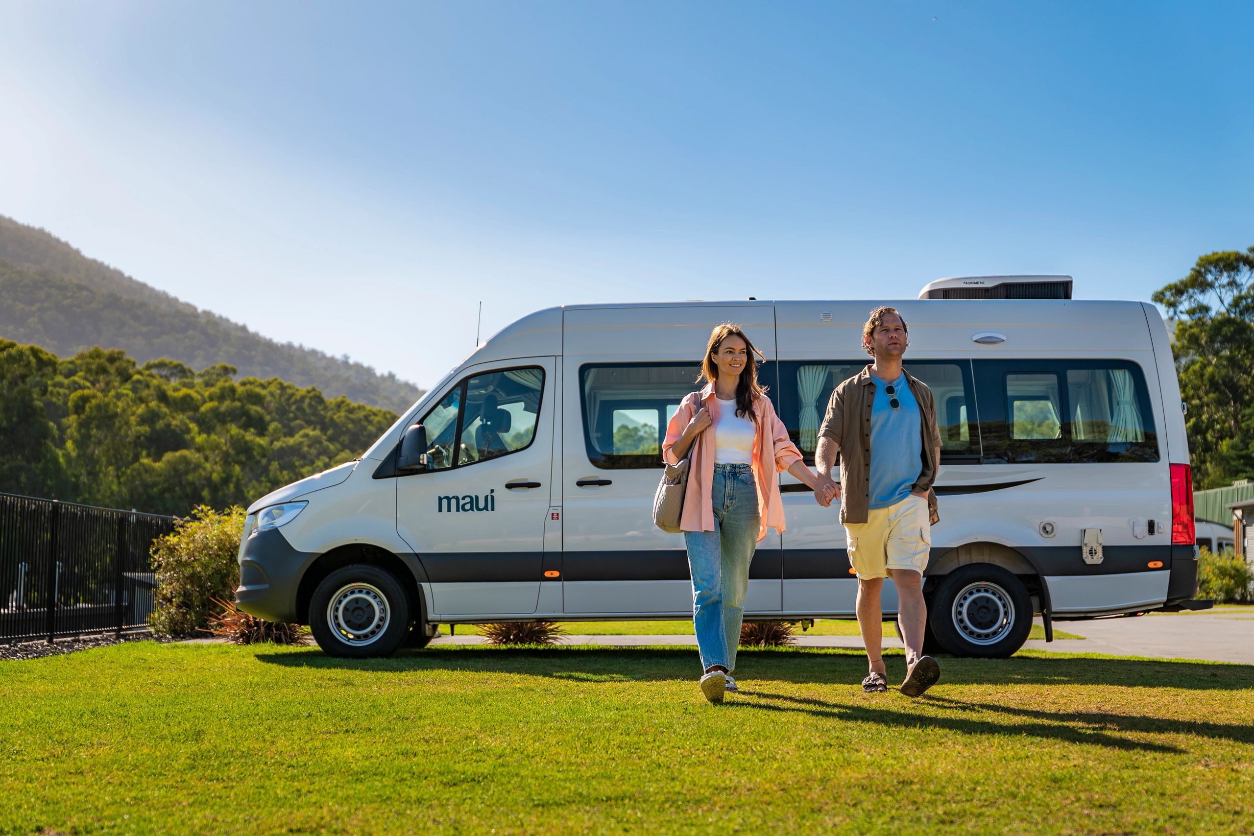 Man en vrouw lopen hand in hand weg van de Maui Ultima camper in de Yarra Valley