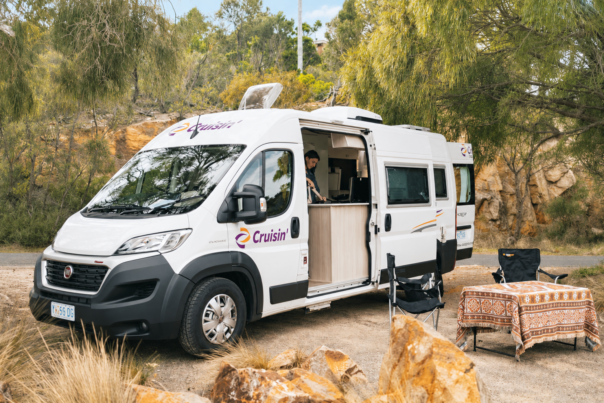 Zijaanzicht van de Cruisin' Sandpiper camper, vrouw staat in keuken binnen