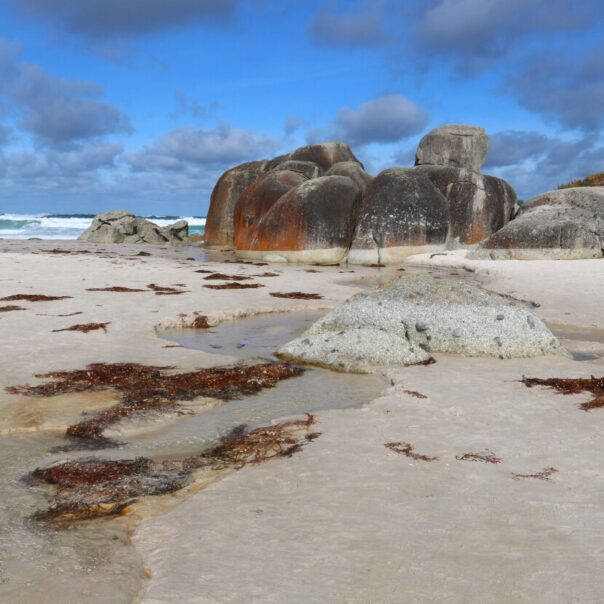 Zicht op grote rode rotsblokken en de zee op Sqeaky Beach in Wilsons promontory