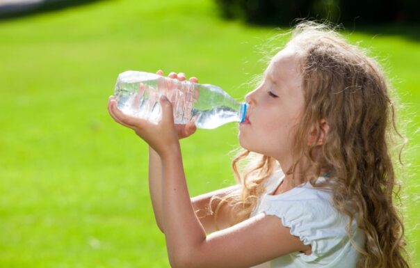Meisje drinkt buiten uit een plastic fles water