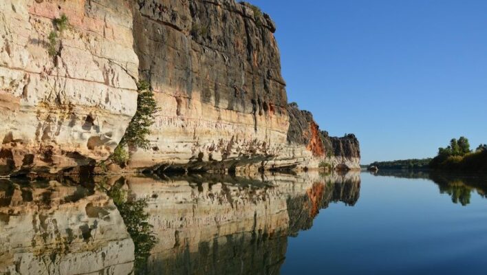 Zicht op gekleurde rotsen met reflectie in het water in de Geiki Gorge in de Kimberley
