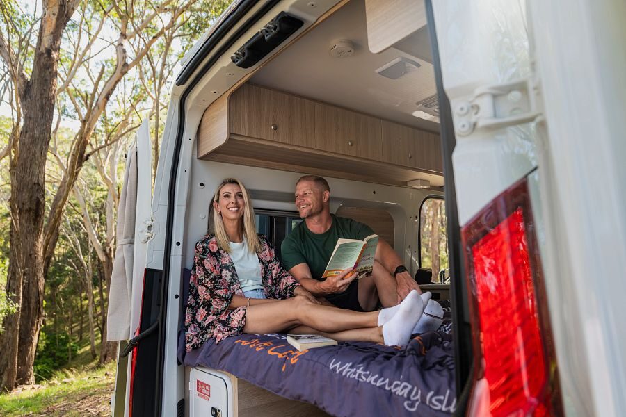 Koppel zit op bed met deuren open in de Britz Trailblazer