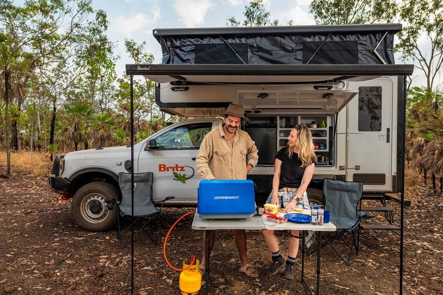 koppel is aan het koken bij de buitenkeuken onder de luifel van de Britz Maverick 4WD