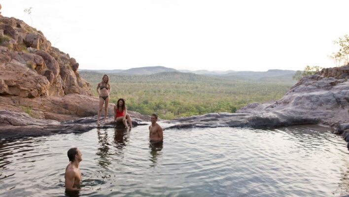 Vrouwen en mannen liggen in de waterpoel bij de Gunlom Falls in Kakadu