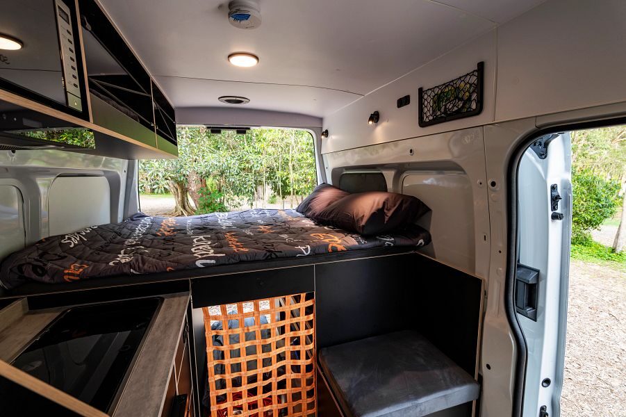 Het tweepersoonsbed achterin de Mighty Double Down camper met de achterdeuren open