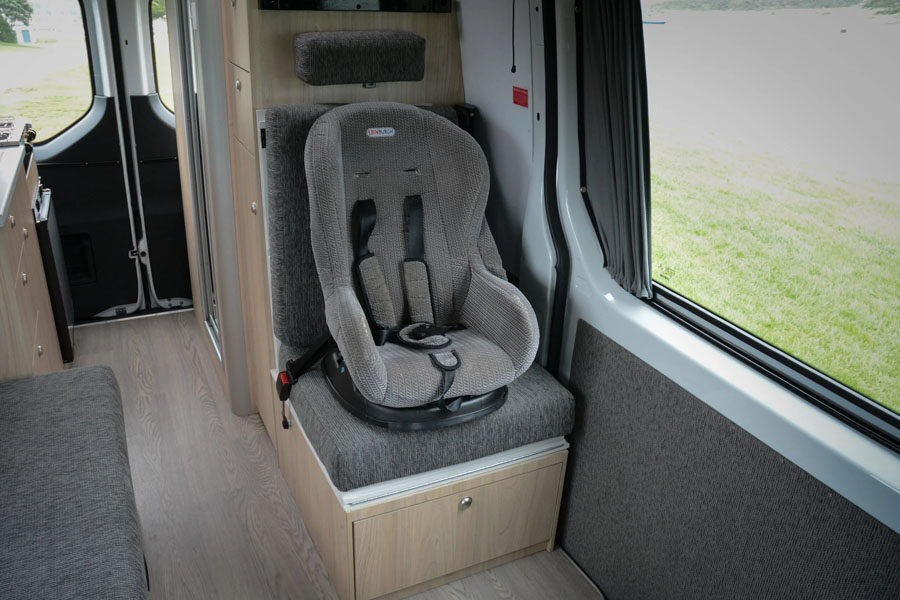 Op de extra zitplaats in de Pacific Horizon 2 plus 1 camper is een kinderautostoel bevestigd