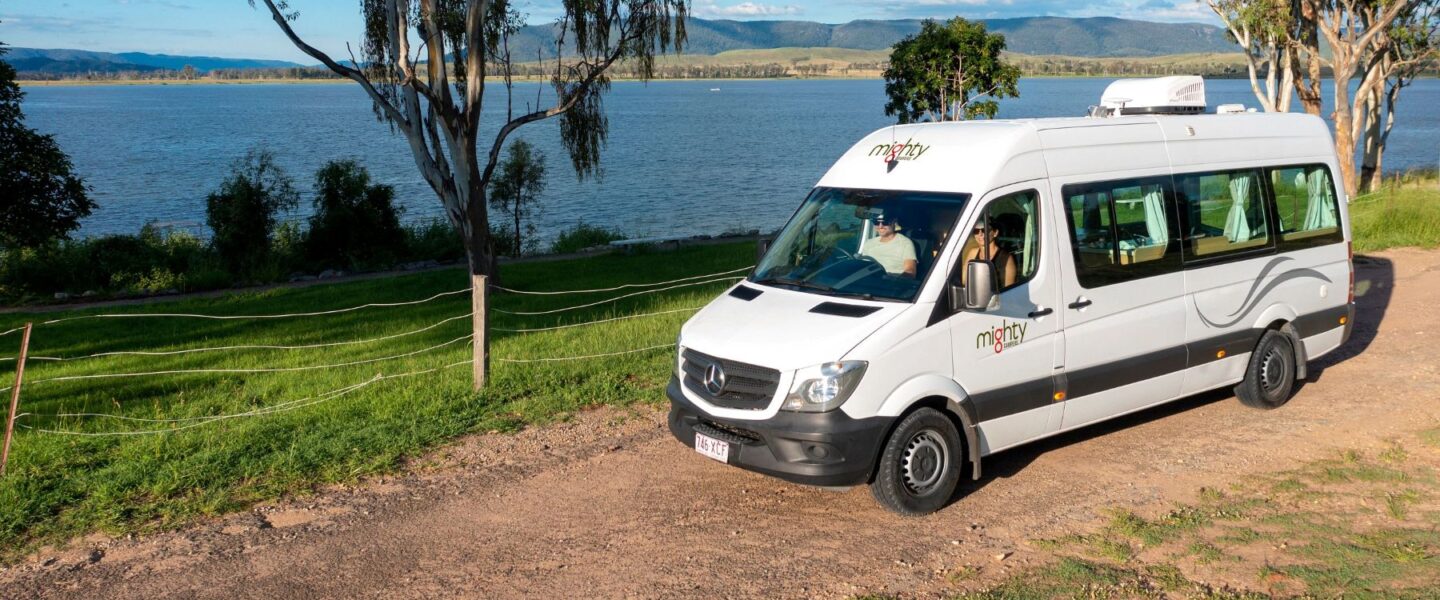 Stel zit in Mighty Deuce camper die geparkeerd staat op een gravelweg langs de zee