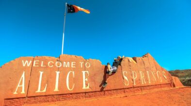 Vrouw ligt op het stenen Alice Springs bord met vlag erop