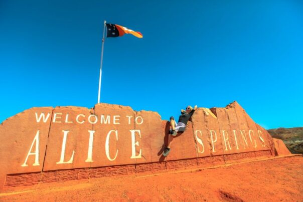 Vrouw ligt op het stenen Alice Springs bord met vlag erop