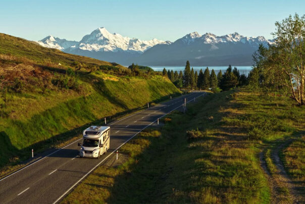 De Britz Wanderer rijdt over een weg met op de achtergrond Lake Pukaki en besneeuwde bergtoppen