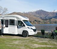 Een stel is aan het wild kamperen met de Britz Odyssey aan een meer