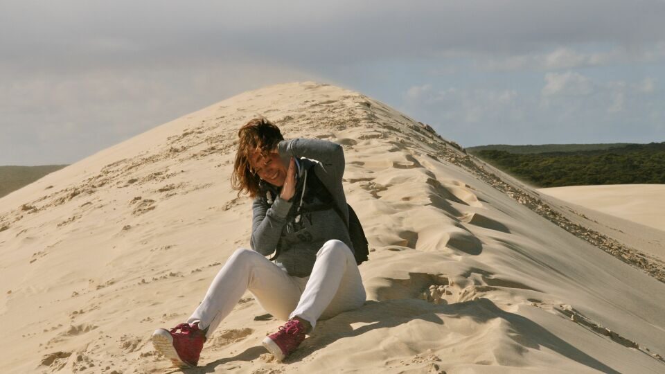 Karin zit op een zandduin in de Little Sahara op Kangaroo Island
