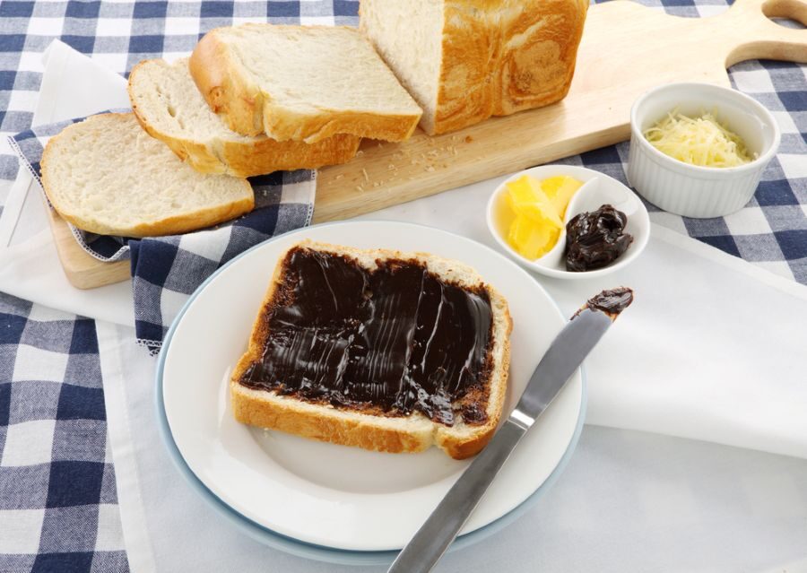 Bord met boterham met vegemite erop en de rest van het brood op de achtergrond