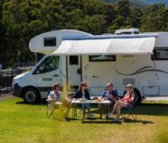 Twee koppels zitten voor de Maui River camper op een camping in de Yarra Valley