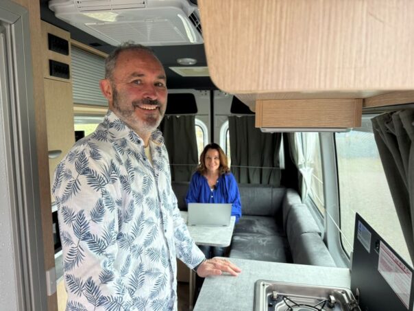 Peter staat in keuken en Karin zit op de bank met haar laptop in een Maui Ultima Plus camper in Woerden