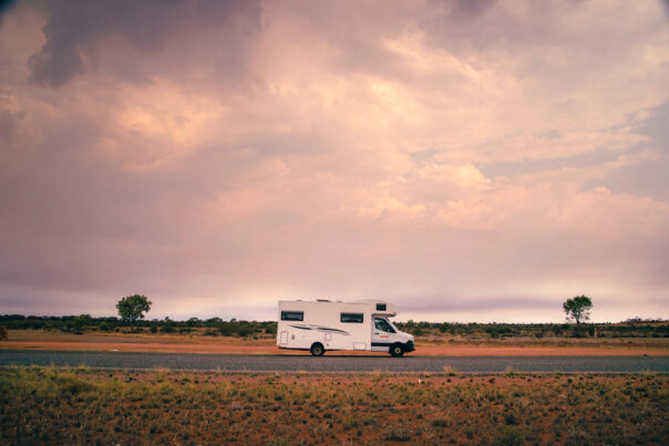 Apollo Euro Deluxe camper rijdt op de weg bij Alice Springs in het Red Centre in de Northern Territory van Australië met rood zand