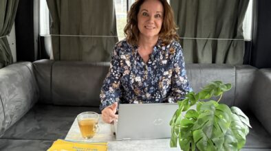 Karin zit in Maui camper met kop thee en laptop voor webinar Australië en Nieuw-Zeeland