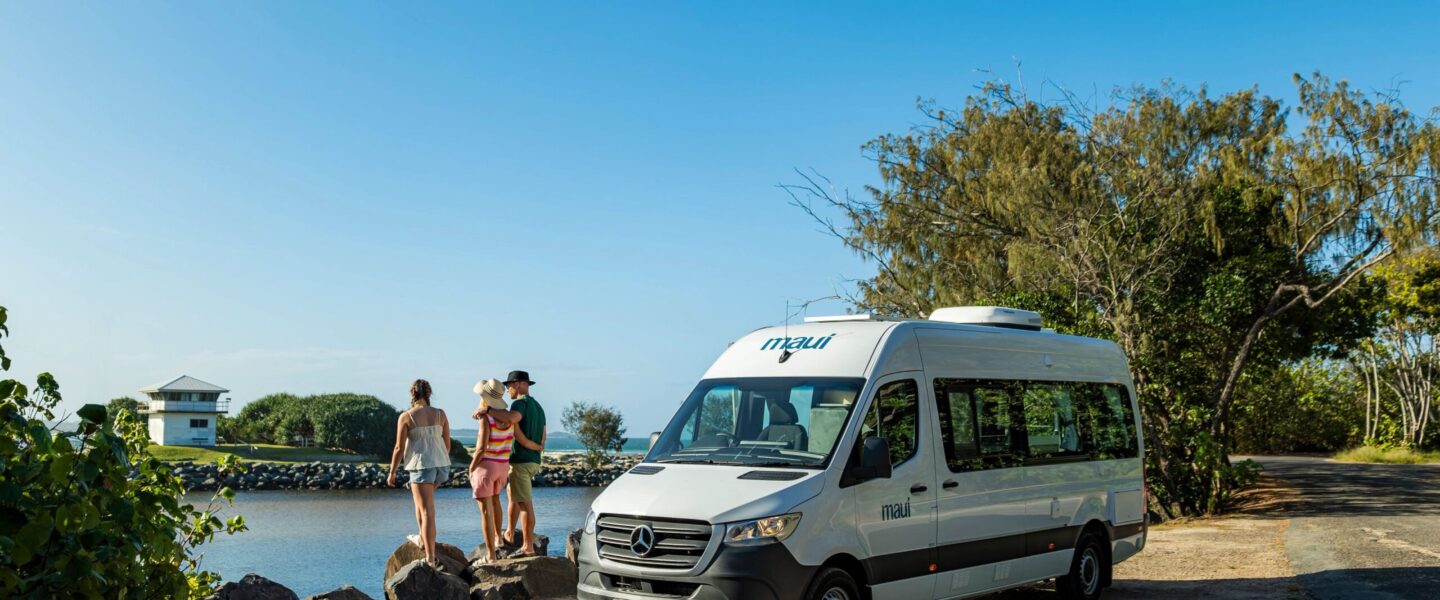 Maui Ultima staat geparkeerd langs het water, mensen staan ernaast