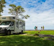 Maui River staat geparkeerd op gras in Australië Noosa en twee stellen kijken in de verte